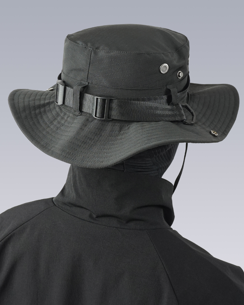 Person wearing a black wide-brimmed hat with a chin strap on a gray background