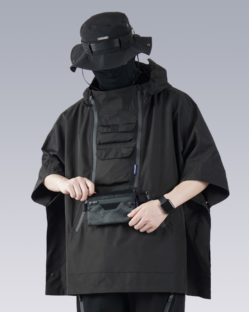 Person wearing a black tactical poncho with a face mask on a gray background