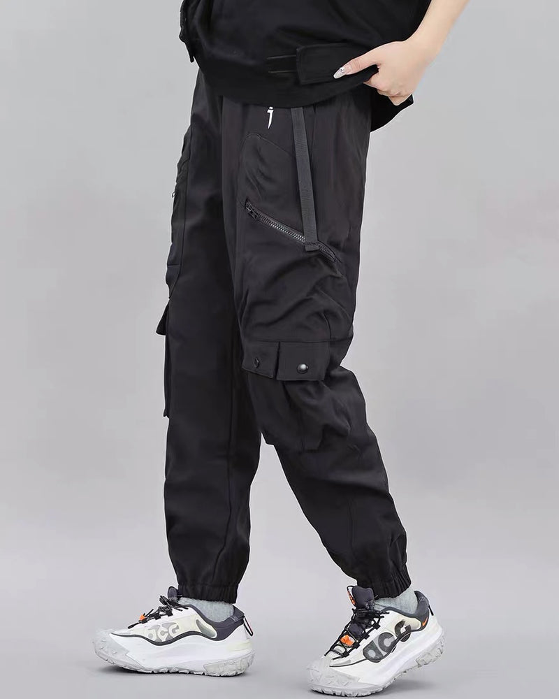 Person wearing black cargo pants on a gray background