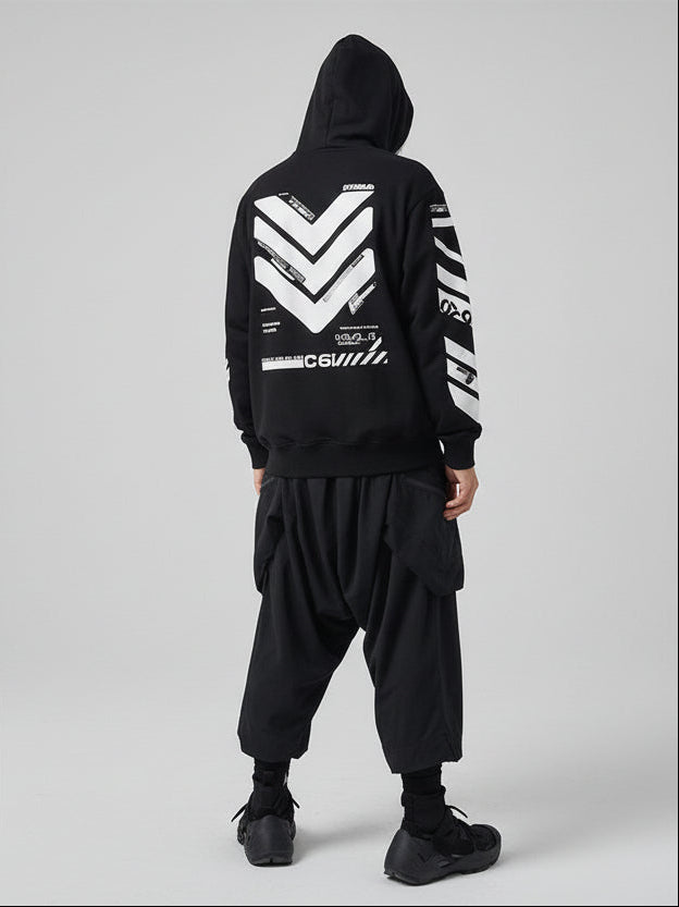 Person wearing a black hoodie with white geometric patterns against a textured wall.