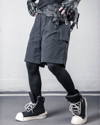 Person wearing tactical shorts, gloves, and boots against a gray background