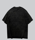 A black mineral-wash short-sleeve t-shirt shown from the back, laid flat against a solid gray background with the brand name 'SHADKW' printed below.