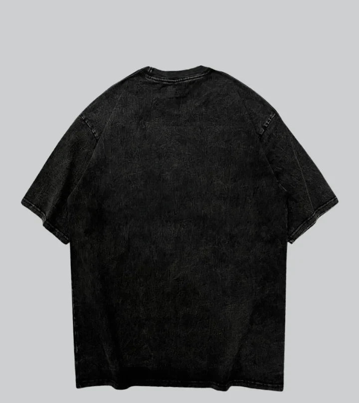 A black mineral-wash short-sleeve t-shirt shown from the back, laid flat against a solid gray background with the brand name 'SHADKW' printed below.