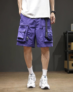 Person wearing blue  cargo shorts and white sneakers against a dark background