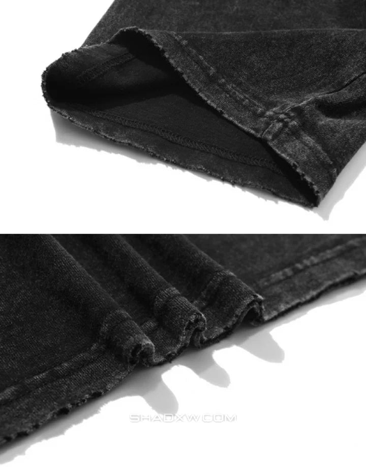 Close-up of a black denim garment showing the folded hem with raw, frayed edges and dark contrast stitching on a white background.