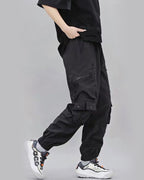 Person wearing black cargo pants with a plain background