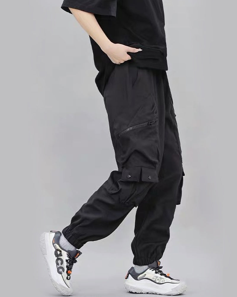Person wearing black cargo pants with a plain background