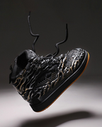Black high-top sneaker with detailed design on a dark background