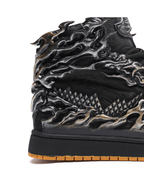Close-up of a black and silver sneaker with detailed design on a white background