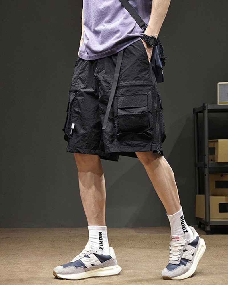 Person wearing black cargo shorts and white sneakers in a casual setting.