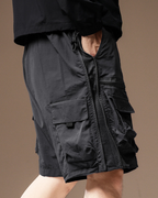 Black cargo shorts worn by a person on a brown background