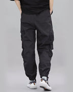 Person wearing black cargo pants on a gray background