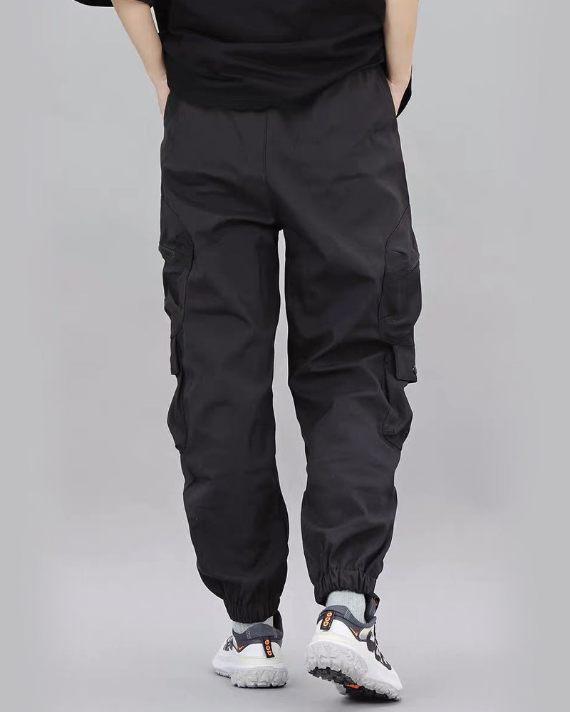 Person wearing black cargo pants on a gray background
