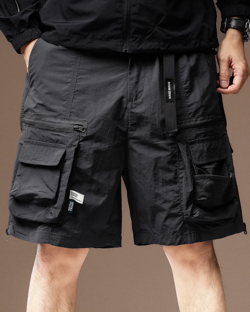 techwear Black cargo shorts worn by a person on a brown background