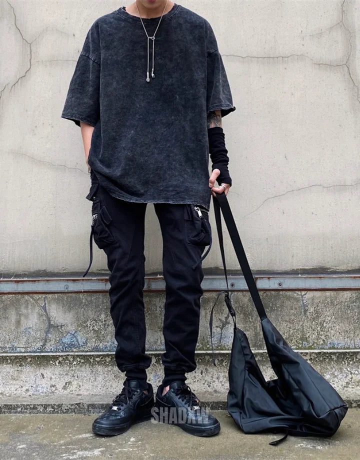 Oversized washed black techwear t-shirt with a long hem, muted charcoal finish, and minimalist urban streetwear styling — view 6