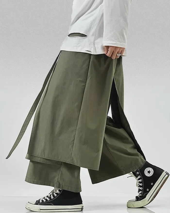 Clotechnow army green wide-leg hakama pants with layered draped panels and side slits worn with black sneakers
