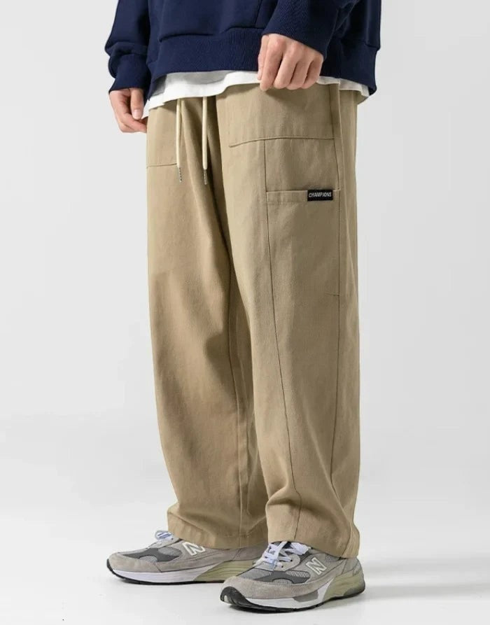 Clotechnow beige wide-leg hakama pants with a drawstring waist and side pocket detail worn with grey sneakers