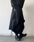 Clotechnow black baggy hakama pants with a wide-leg draped silhouette and side pockets worn with black boots