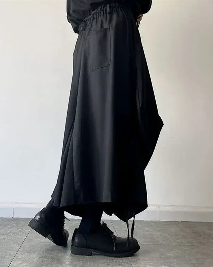 Clotechnow black baggy hakama pants with a wide-leg draped silhouette and elastic waist, styled with black shoes.