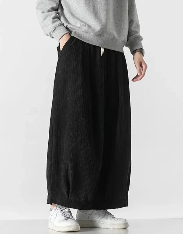 Clotechnow black cord texture hakama pants with a wide-leg draped silhouette worn with a grey sweatshirt and sneakers