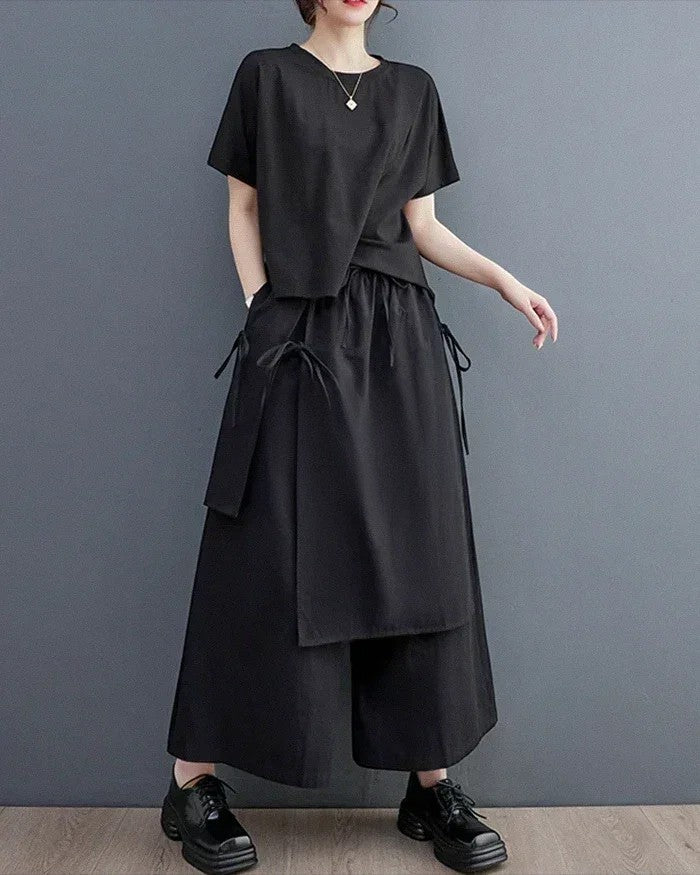 A model wearing Clotechnow black double-layer wide-leg hakama pants with a matching short-sleeve top and black shoes.