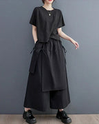 A model wearing Clotechnow black double-layer wide-leg hakama pants with a matching short-sleeve top and black shoes.