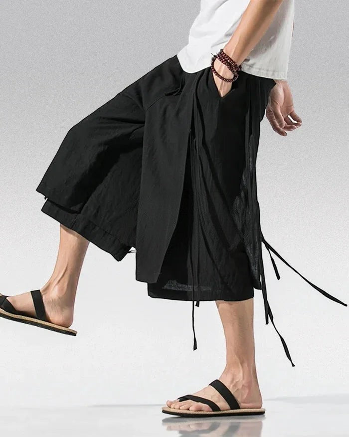 Clotechnow black sarouelle drape hakama pants with wide-leg silhouette and side tie details worn with sandals