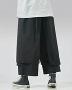 Clotechnow black wide-leg hakama pants with a layered draped silhouette and cropped hem worn with high-top sneakers