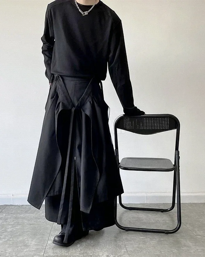 Clotechnow modular black skirted hakama pants featuring a layered hybrid silhouette on a model standing by a chair.