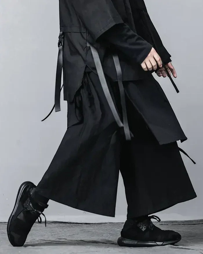 Clotechnow black wide-leg hakama pants with pleated structure and side strap details worn with black sneakers