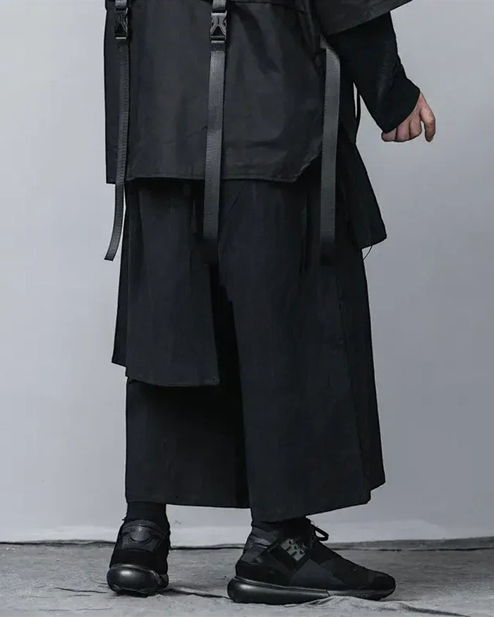 Clotechnow black wide-leg hakama pants with pleated structure and techwear straps worn with black sneakers