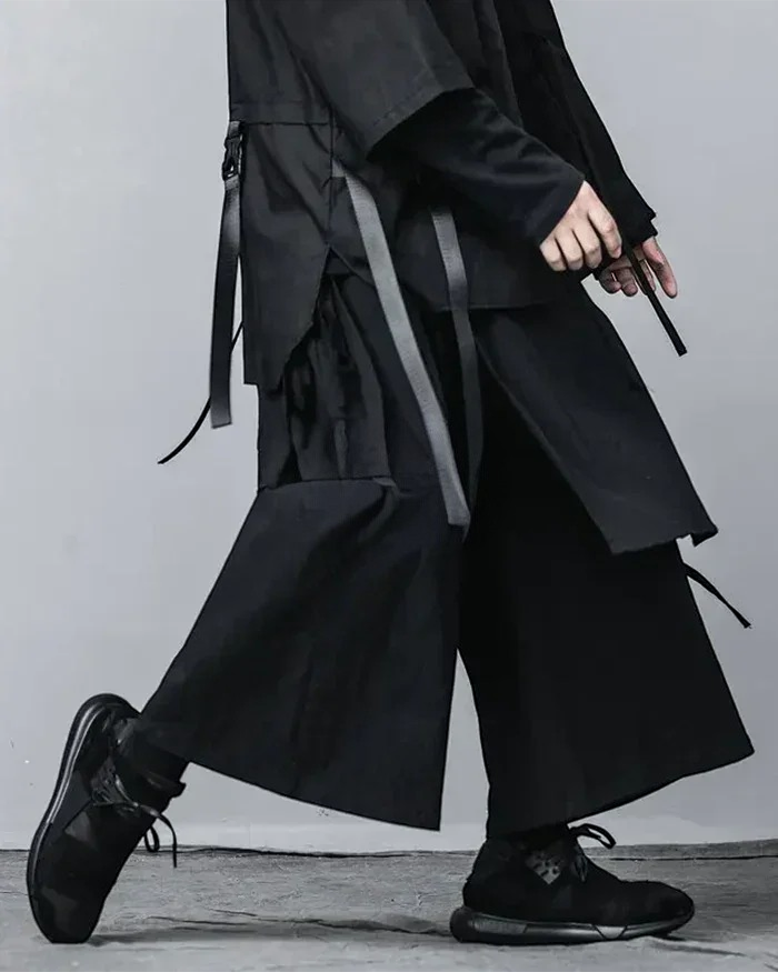 Clotechnow black wide-leg hakama pants with pleated structure and side strap details worn with black sneakers