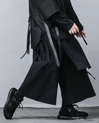 Clotechnow black wide-leg hakama pants with pleated structure and side strap details worn with black sneakers