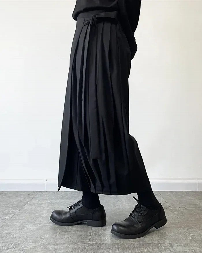 Clotechnow black wide-leg hakama pants with pleated detailing and a draped silhouette worn with black leather shoes