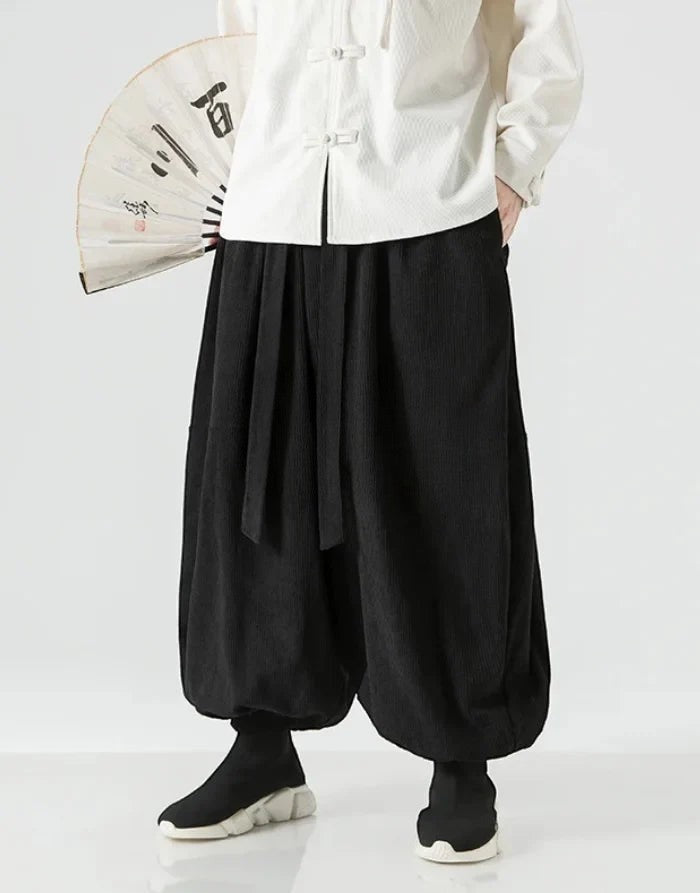 Clotechnow black wide-leg hakama pants with ribbon tie waist and draped silhouette worn with a white top and fan