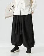 Clotechnow black wide-leg hakama pants with ribbon tie waist and draped silhouette worn with a white top and fan