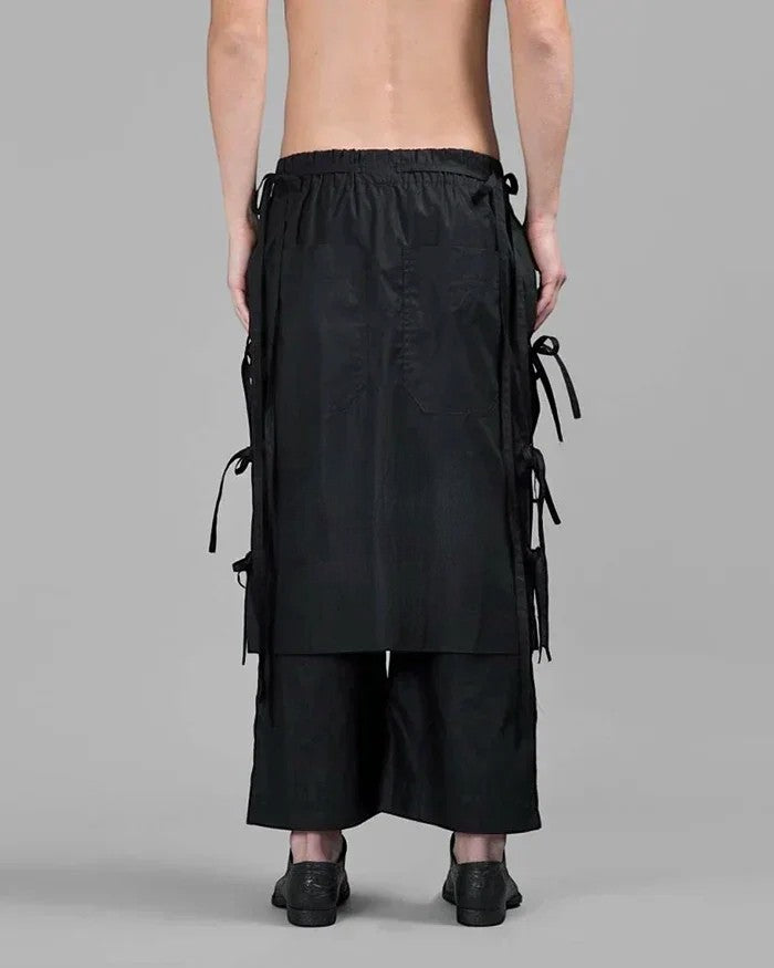 Clotechnow black wide-leg hakama pants with side tie details and layered fabric panels viewed from the back.