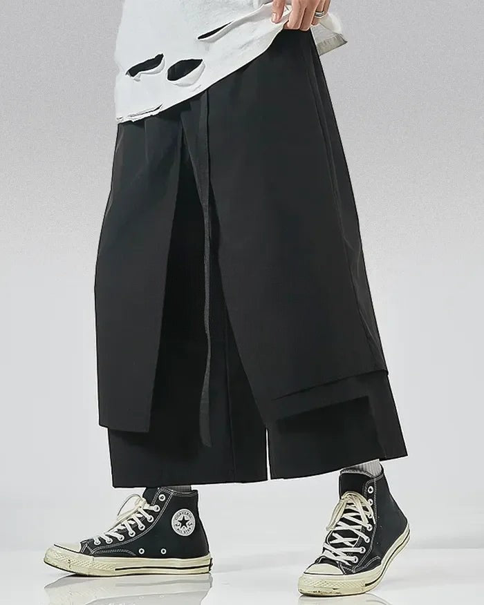 Clotechnow black wide-leg hakama pants with a draped layered silhouette worn with high-top sneakers