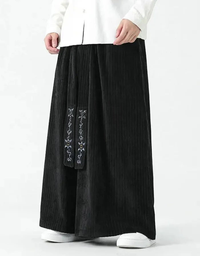 Clotechnow black wide-leg hakama pants with vertical texture and embroidered detailing worn with white sneakers