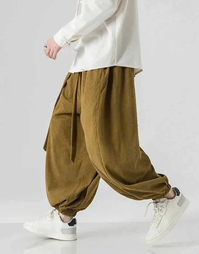 Clotechnow brown corduroy hakama pants with a wide-leg silhouette and ribbon tie detail worn with white sneakers