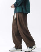 Clotechnow brown wide-leg hakama pants with a drawstring waist, styled with a striped top and white sneakers.