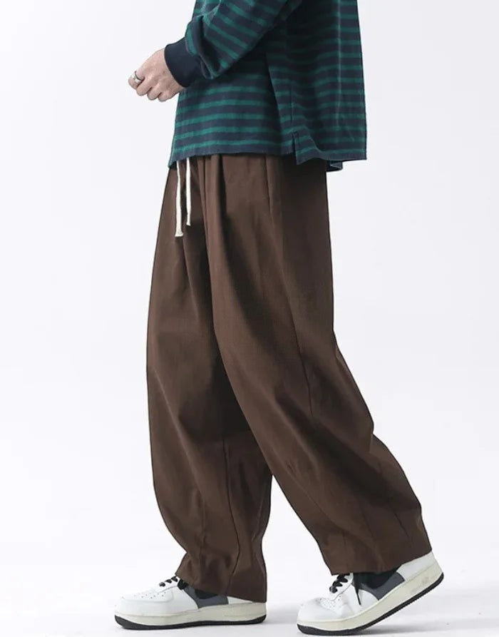 Clotechnow brown wide-leg hakama pants with a drawstring waist, styled with a striped top and white sneakers.