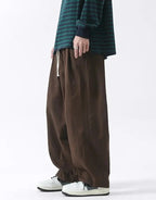Clotechnow brown wide-leg Hakama pants with a drawstring waist, styled with a striped long-sleeve shirt.