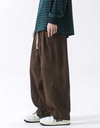 Clotechnow brown wide-leg hakama pants with a drawstring waist, styled with a striped long-sleeve shirt and sneakers.