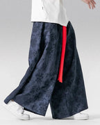 Clotechnow dark blue wide-leg hakama pants with a subtle glyph pattern and a contrasting red fabric belt detail.