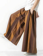 Clotechnow earth tone striped hakama pants with a wide-leg draped silhouette worn by a person in white sneakers