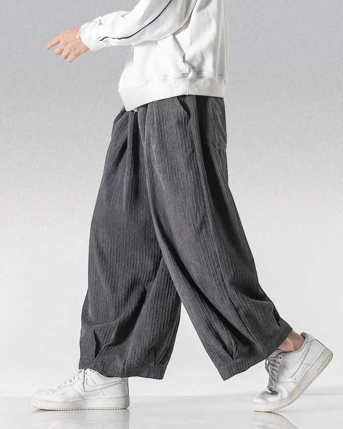 Clotechnow gray wide-leg Hakama pants with a textured fabric and draped silhouette worn with white sneakers