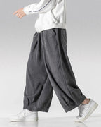 Clotechnow gray wide-leg Hakama pants with a textured fabric and draped silhouette worn with white sneakers