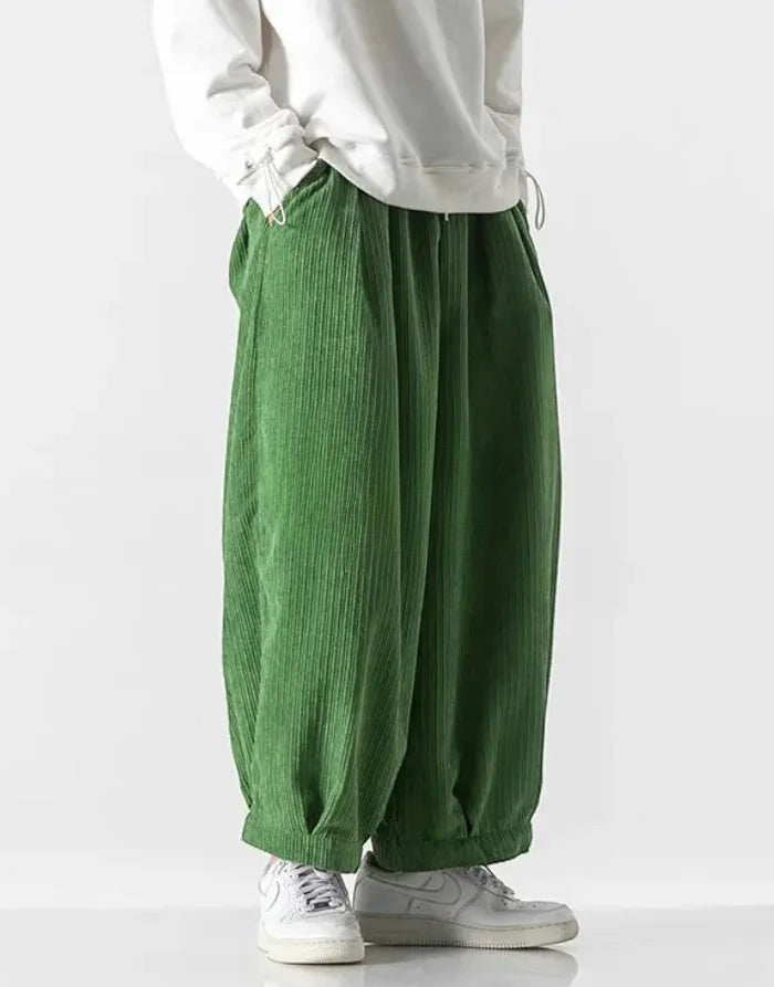Clotechnow green corduroy hakama pants with a wide-leg draped silhouette and elasticated hem worn with white sneakers