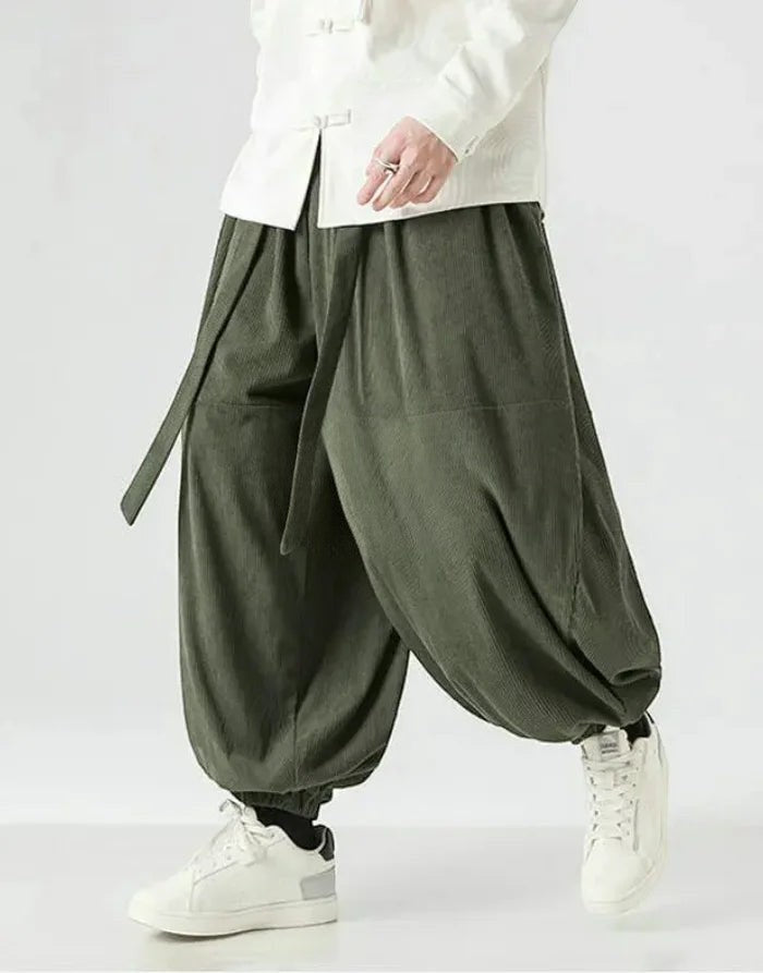 Clotechnow green corduroy hakama pants with a ribbon tie waist and wide-leg draped silhouette worn with white sneakers